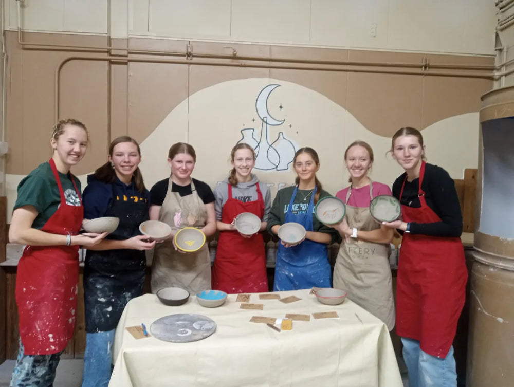 Group of girls holding finished pottery bowls