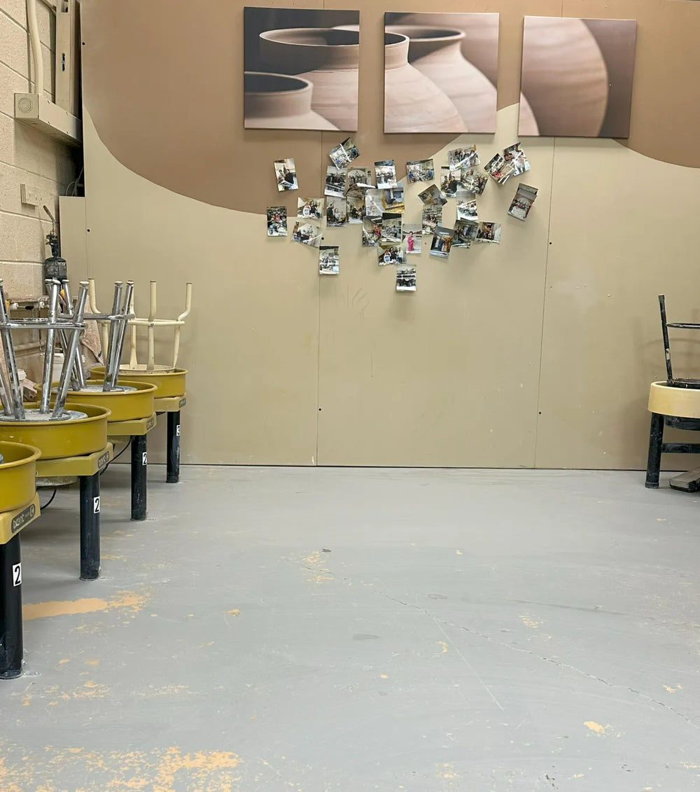 Studio wall with pottery shelves and class photos