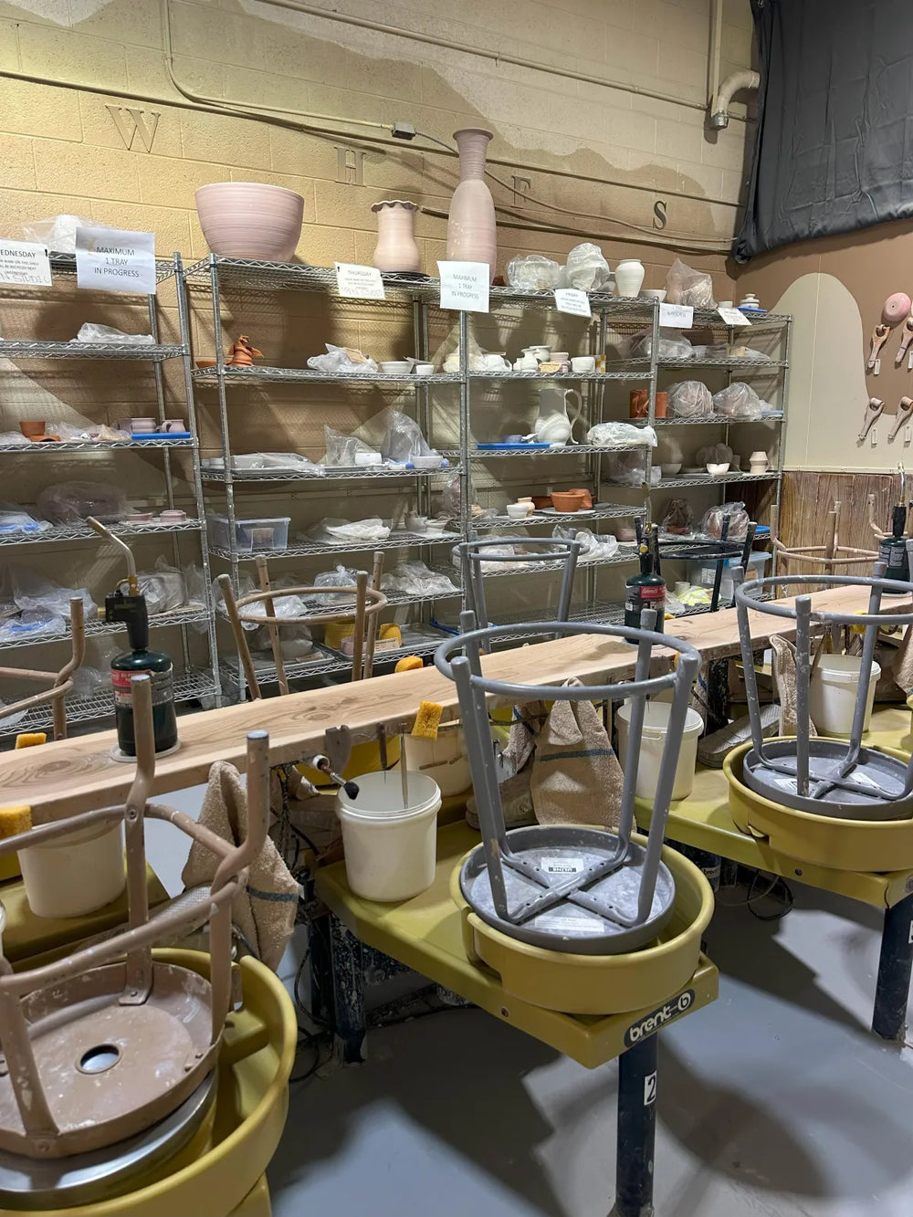 Pottery wheels lined up with chairs in the studio